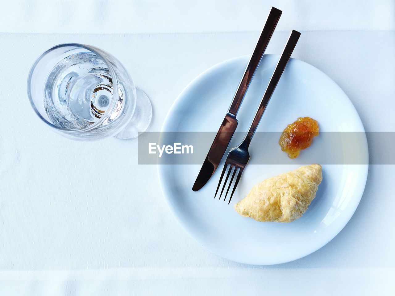 High angle view of croissant in plate by glass on table