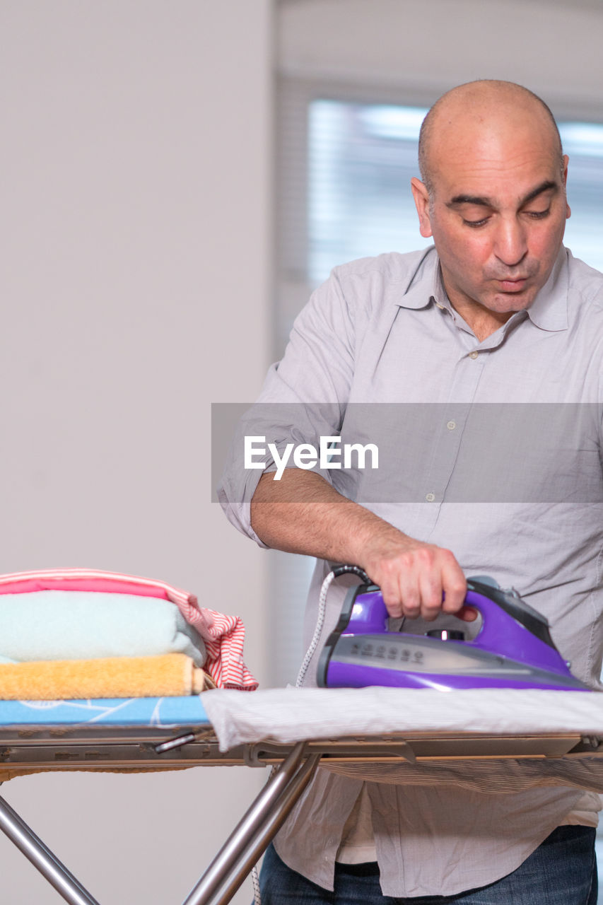 Man ironing clothes at home