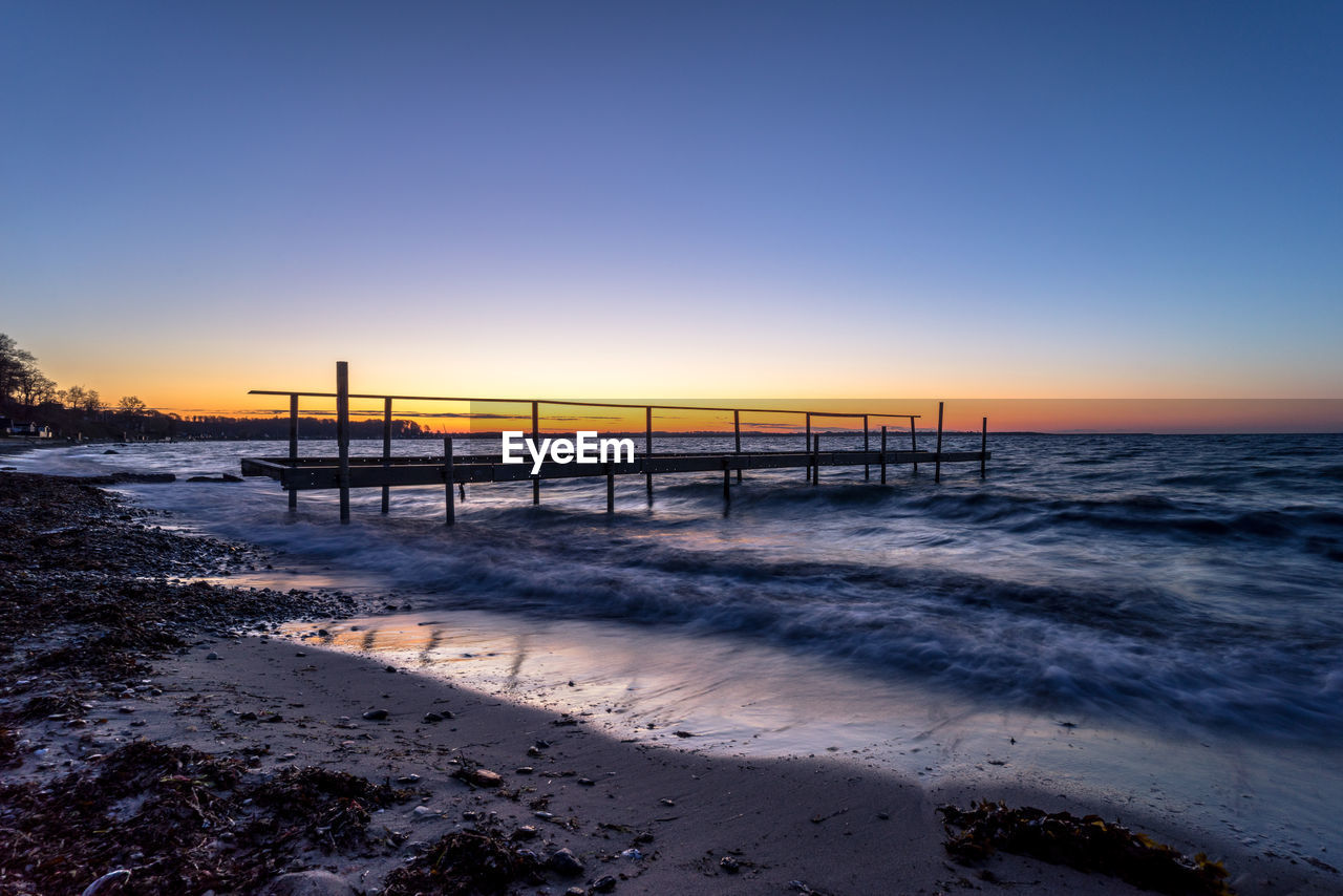 PIER ON SEA AGAINST CLEAR SKY DURING SUNSET