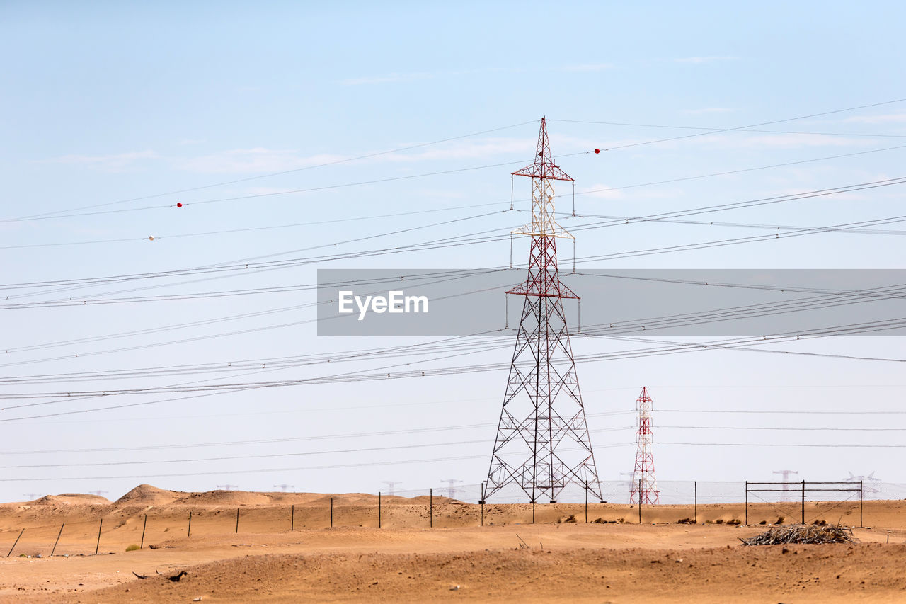 ELECTRICITY PYLON ON FIELD AGAINST SKY