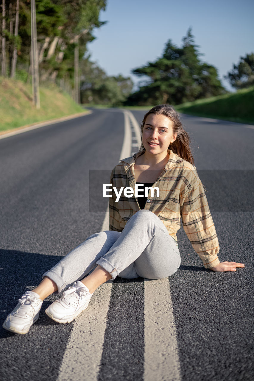 Portrait of young woman sitting on road