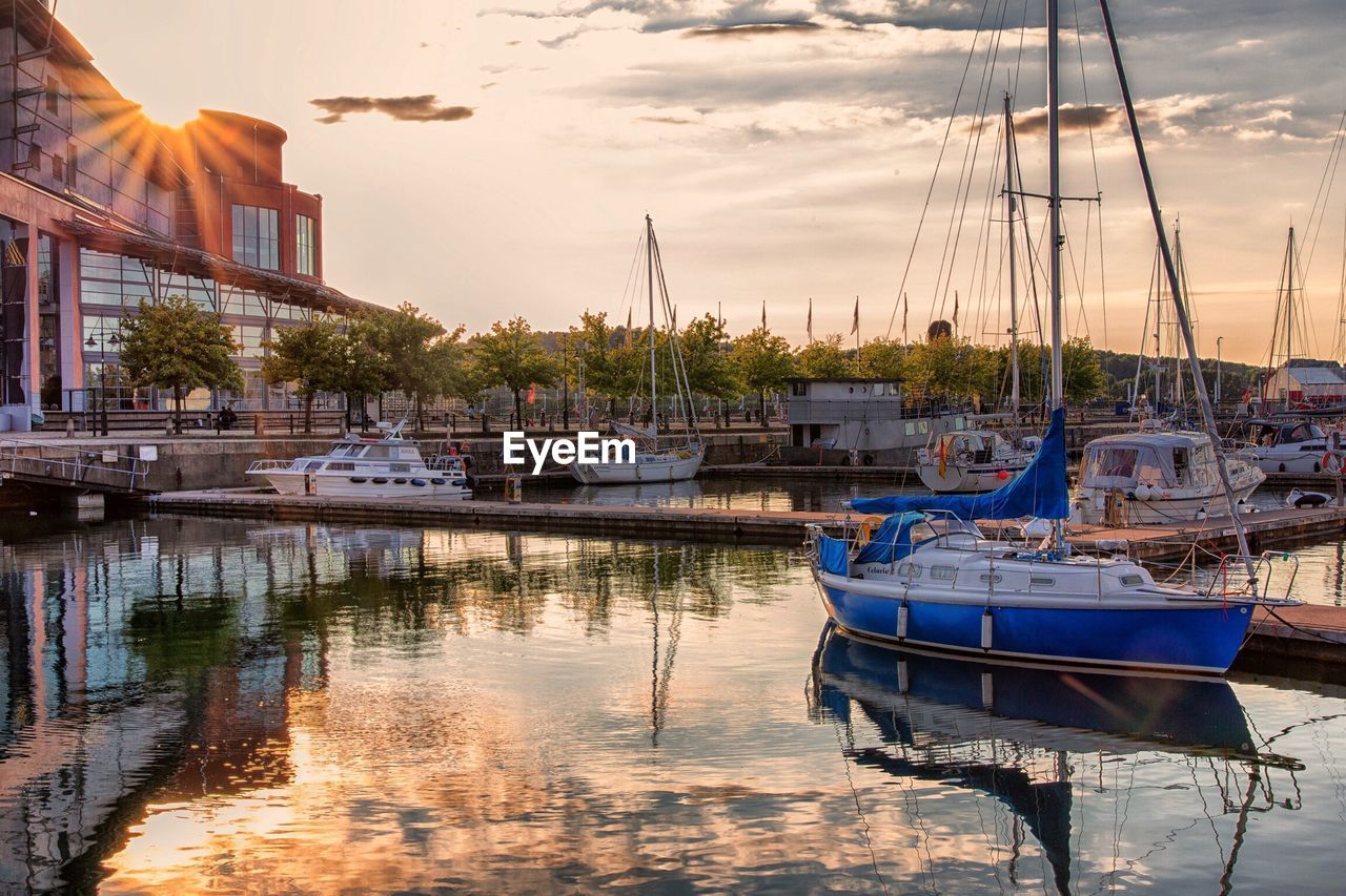 BOATS MOORED AT HARBOR AGAINST SKY