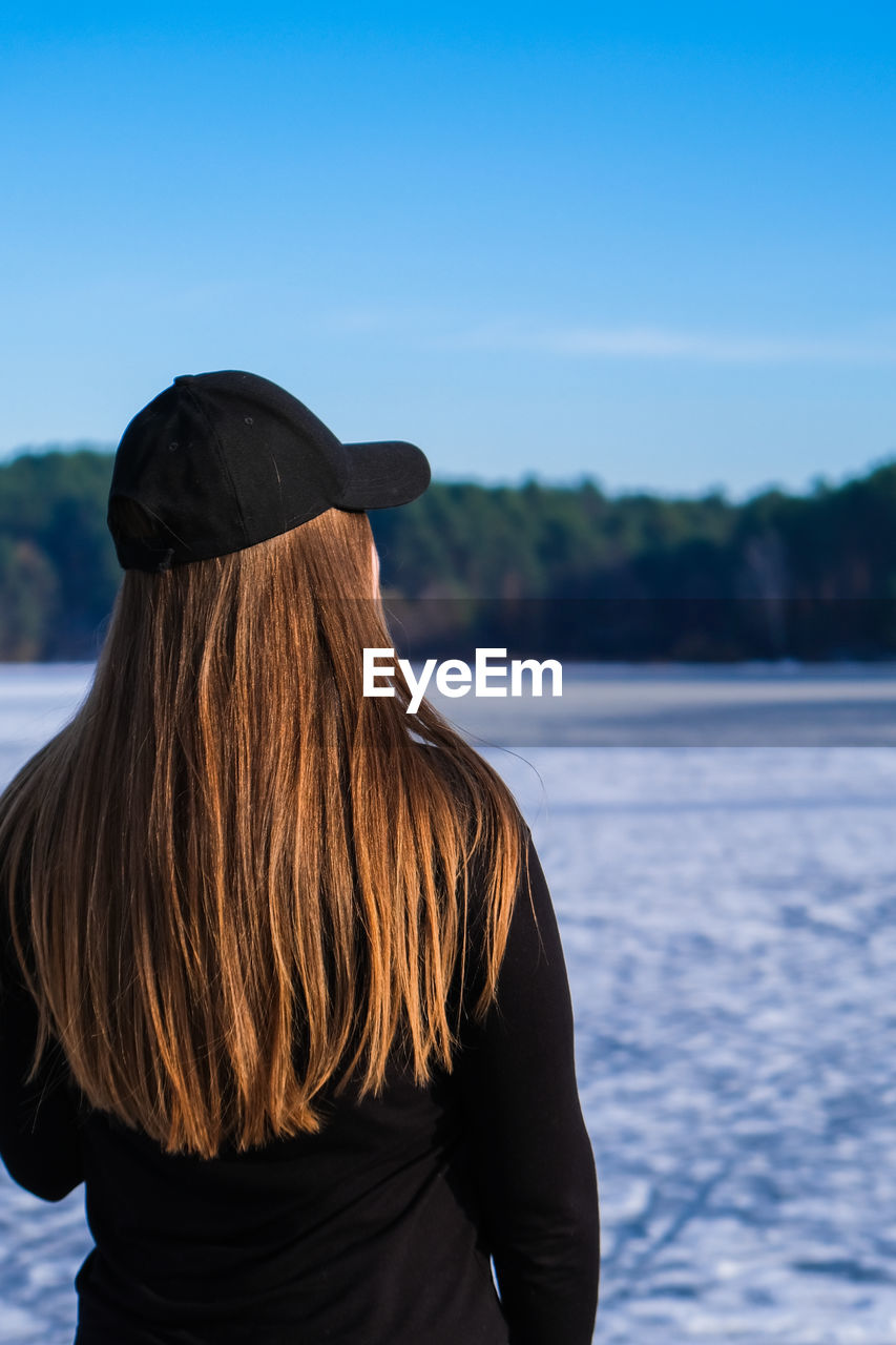 Young female woman back to the camera with long hair in a snow landscape. happy hipster 