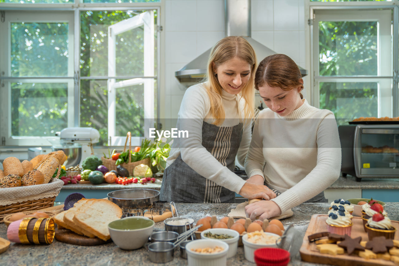 Mother and daughter working together happily to make sweets on holiday.