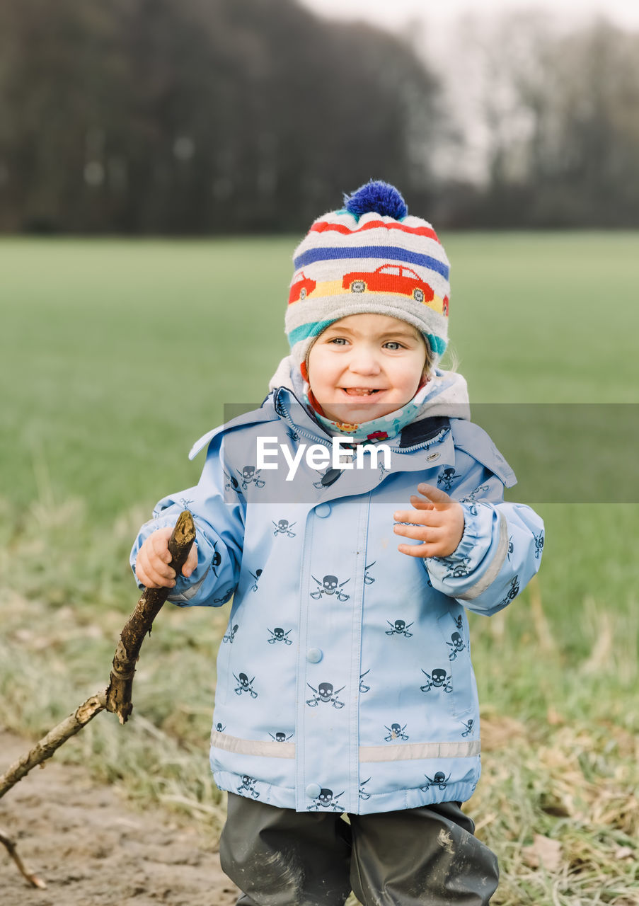 PORTRAIT OF CUTE BABY GIRL STANDING ON FIELD