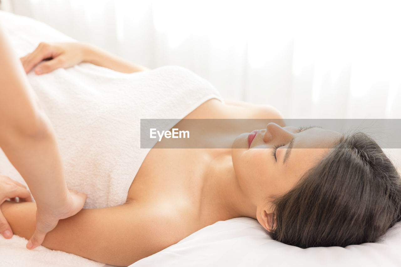 In a spa salon, a young woman enjoys massage therapy.