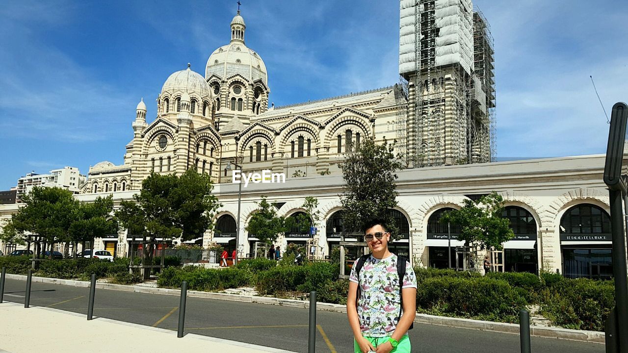 Portrait of young man standing against marseille cathedral on sunny day