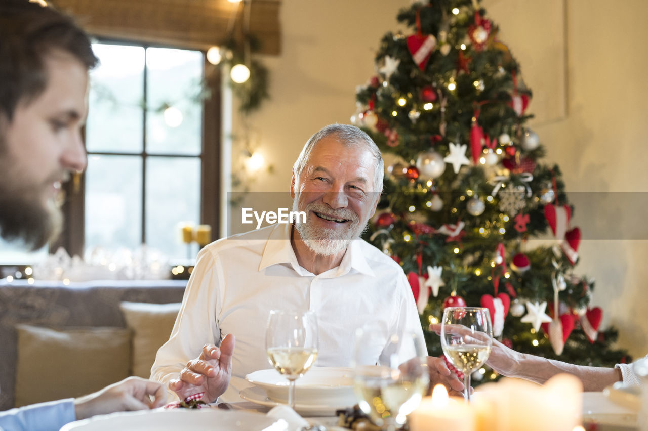 Smiling senior man looking at adult son at christmas dinner table