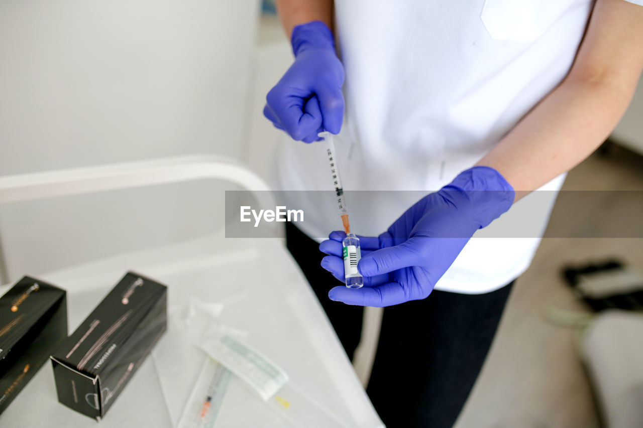 Midsection of doctor holding syringe at clinic