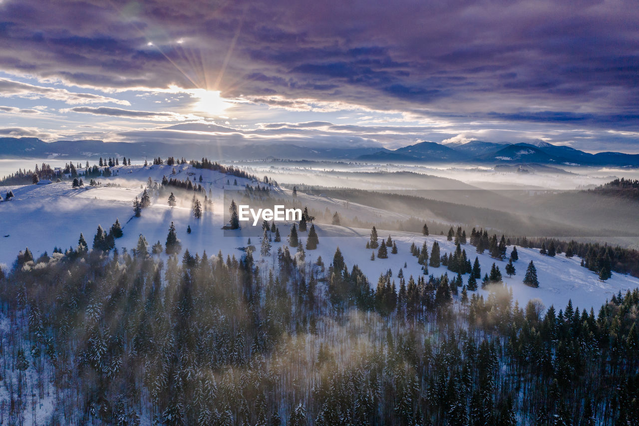 Scenic view of snow covered landscape against sky during sunset