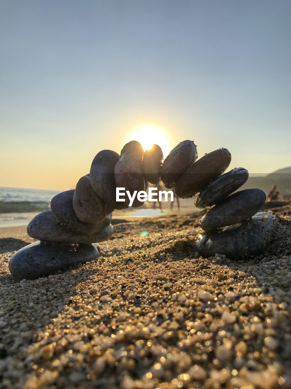 Stack of stones on beach against sky during sunset