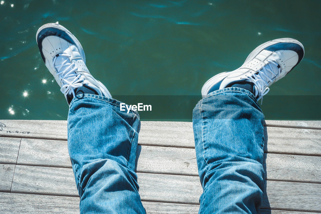 Low section of man on pier over lake