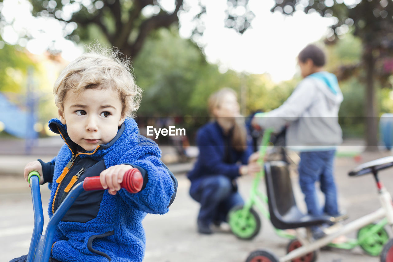 Boy looking away while riding tricycle on playground
