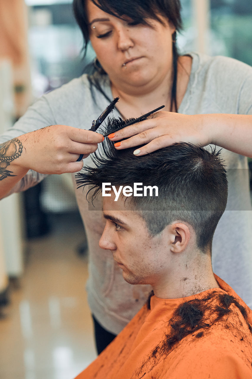 Woman cutting man hair in salon