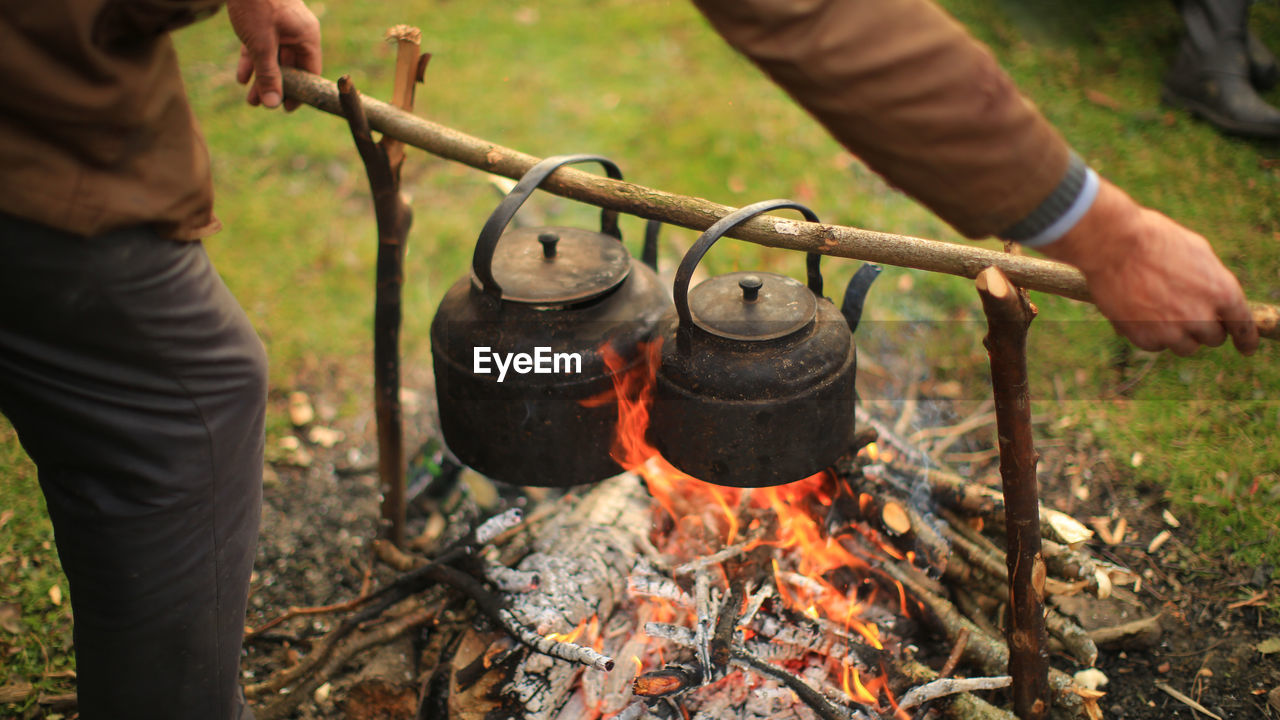 Midsection of man preparing food over bonfire