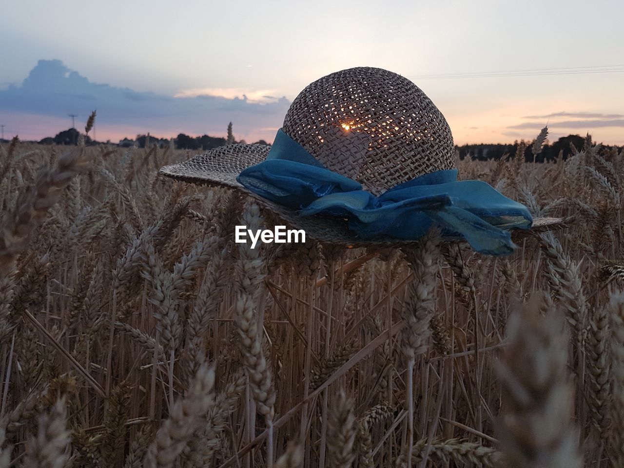 Close-up of hat on field against sky during sunset