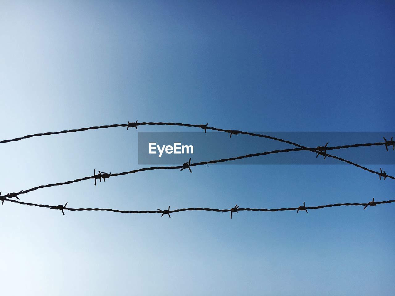 Barbed wire against clear blue sky