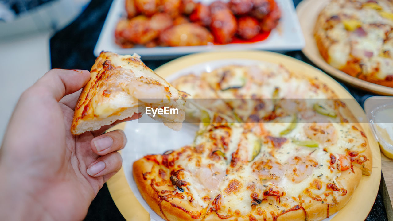 CLOSE-UP OF PERSON HOLDING PIZZA