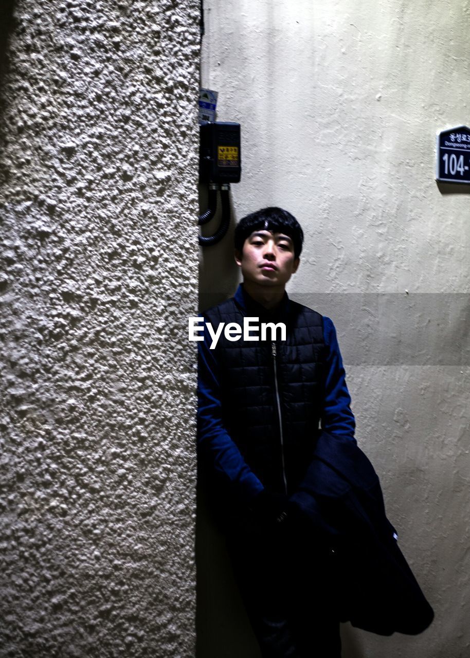 Portrait of young man leaning on wall at night