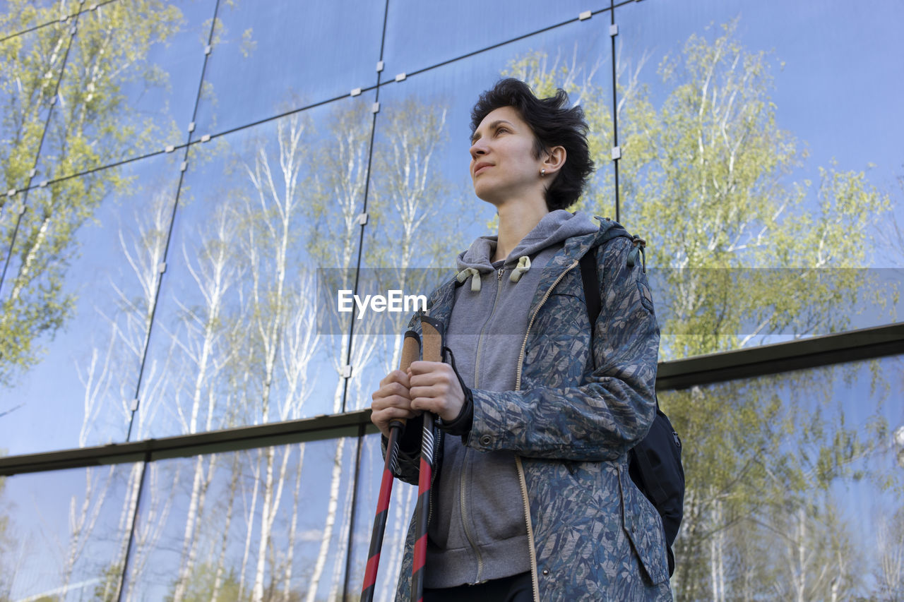 Pole walking in urban area, city beautiful happy caucasian woman training with sticks outdoor