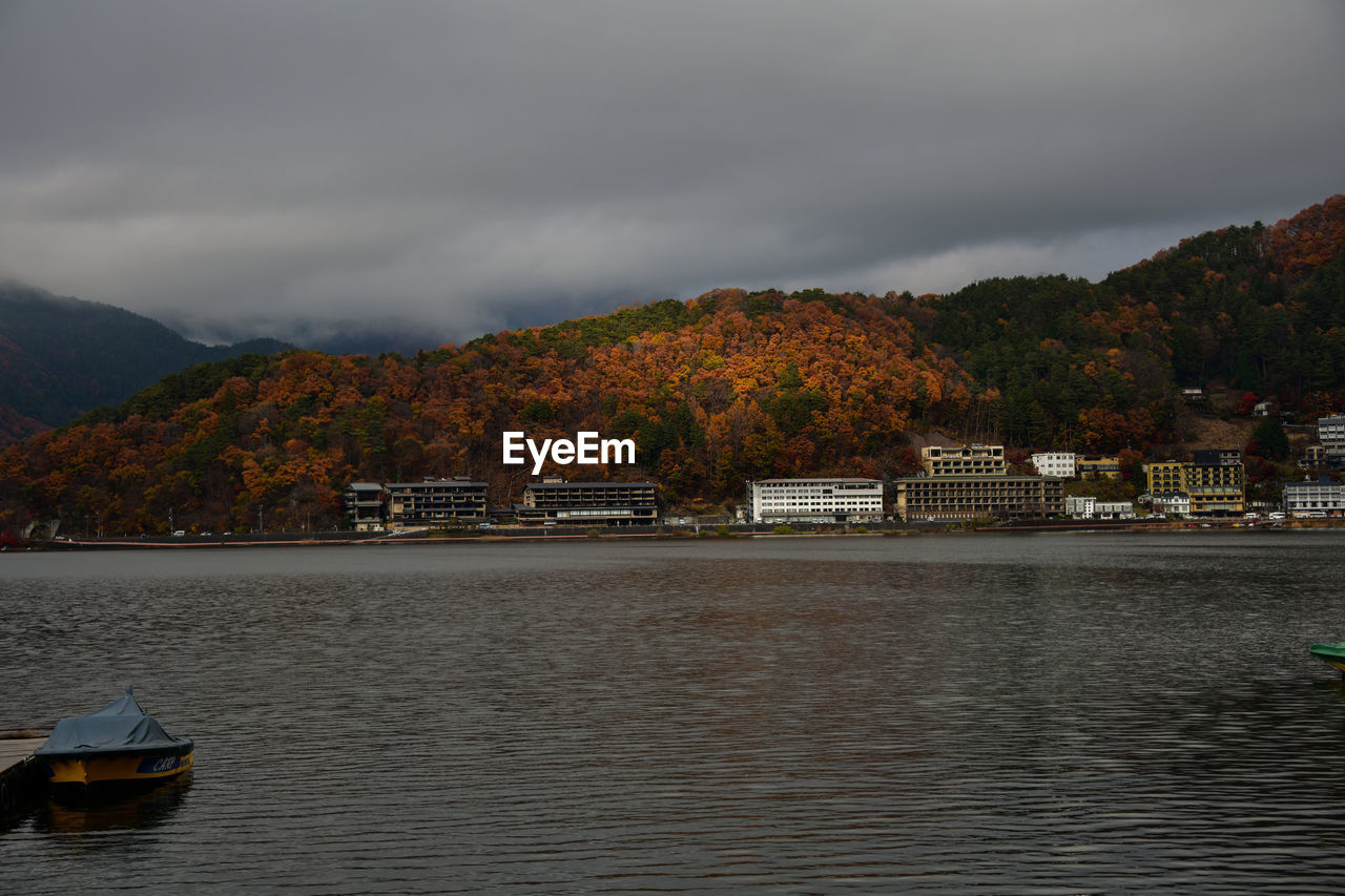 Scenic view of river by buildings against sky