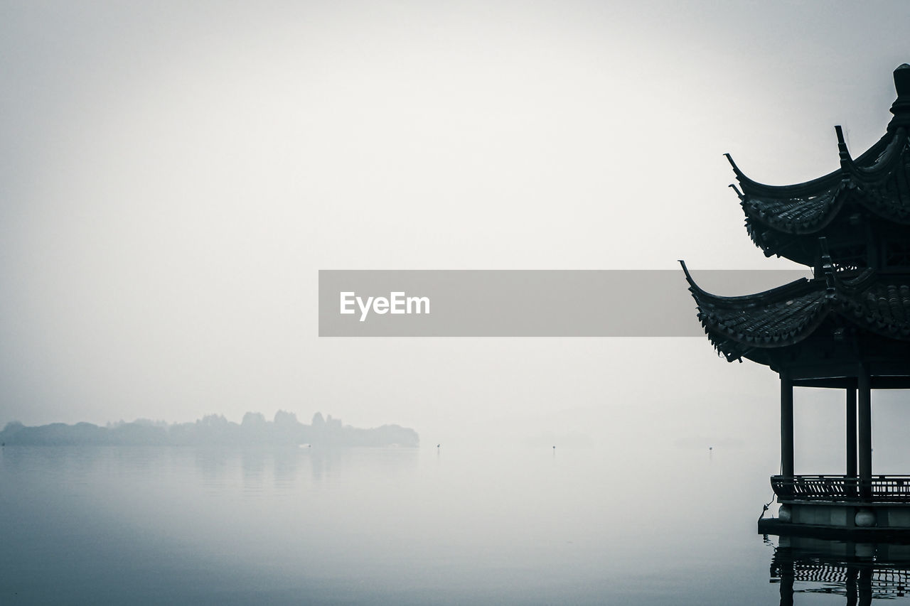 Cropped image of traditional gazebos on lake during foggy weather