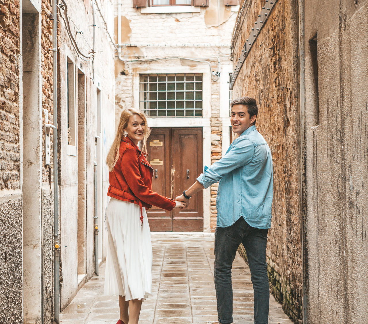 Portrait of young couple running on footpath