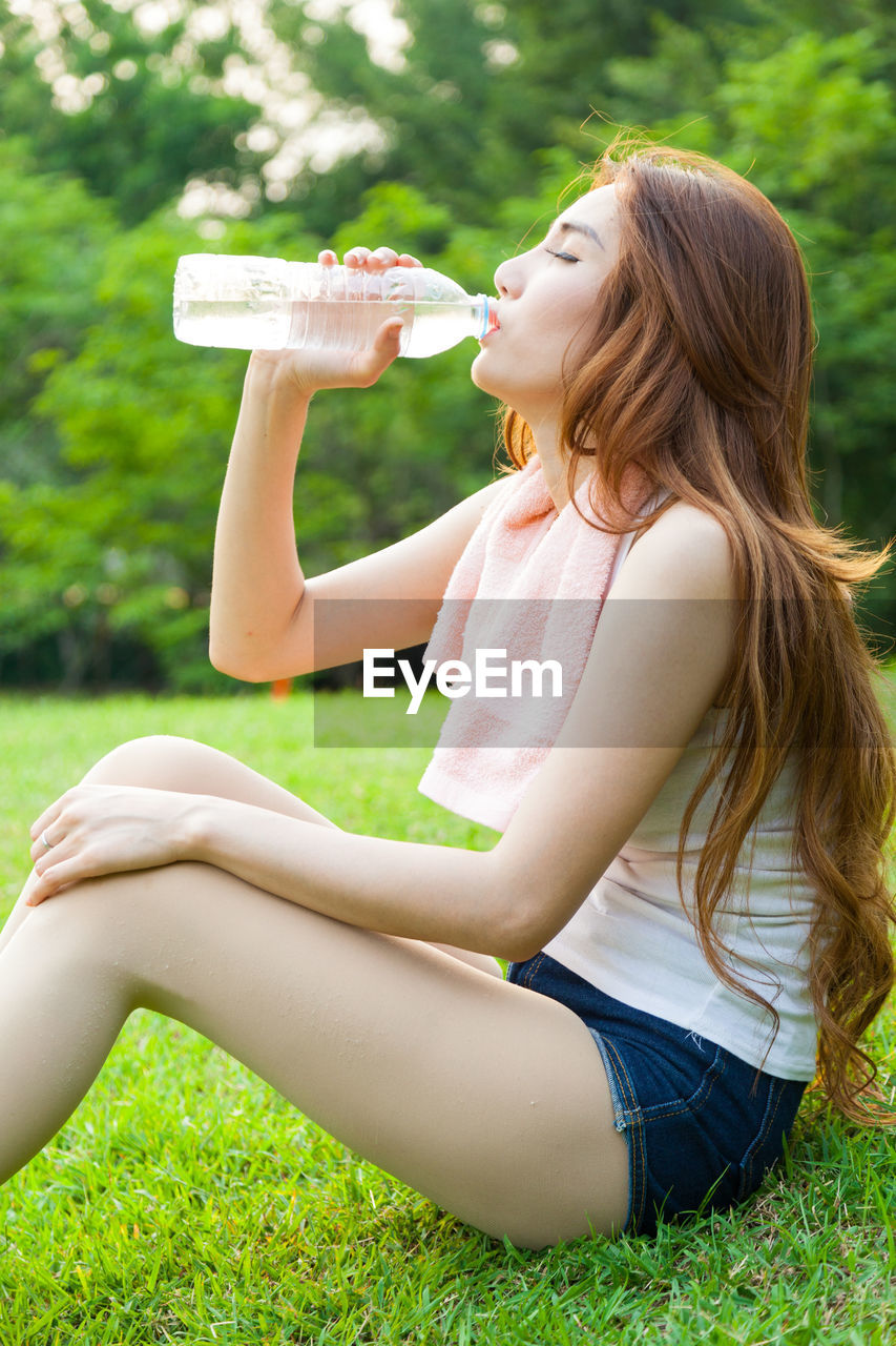 SIDE VIEW OF BEAUTIFUL YOUNG WOMAN DRINKING WATER