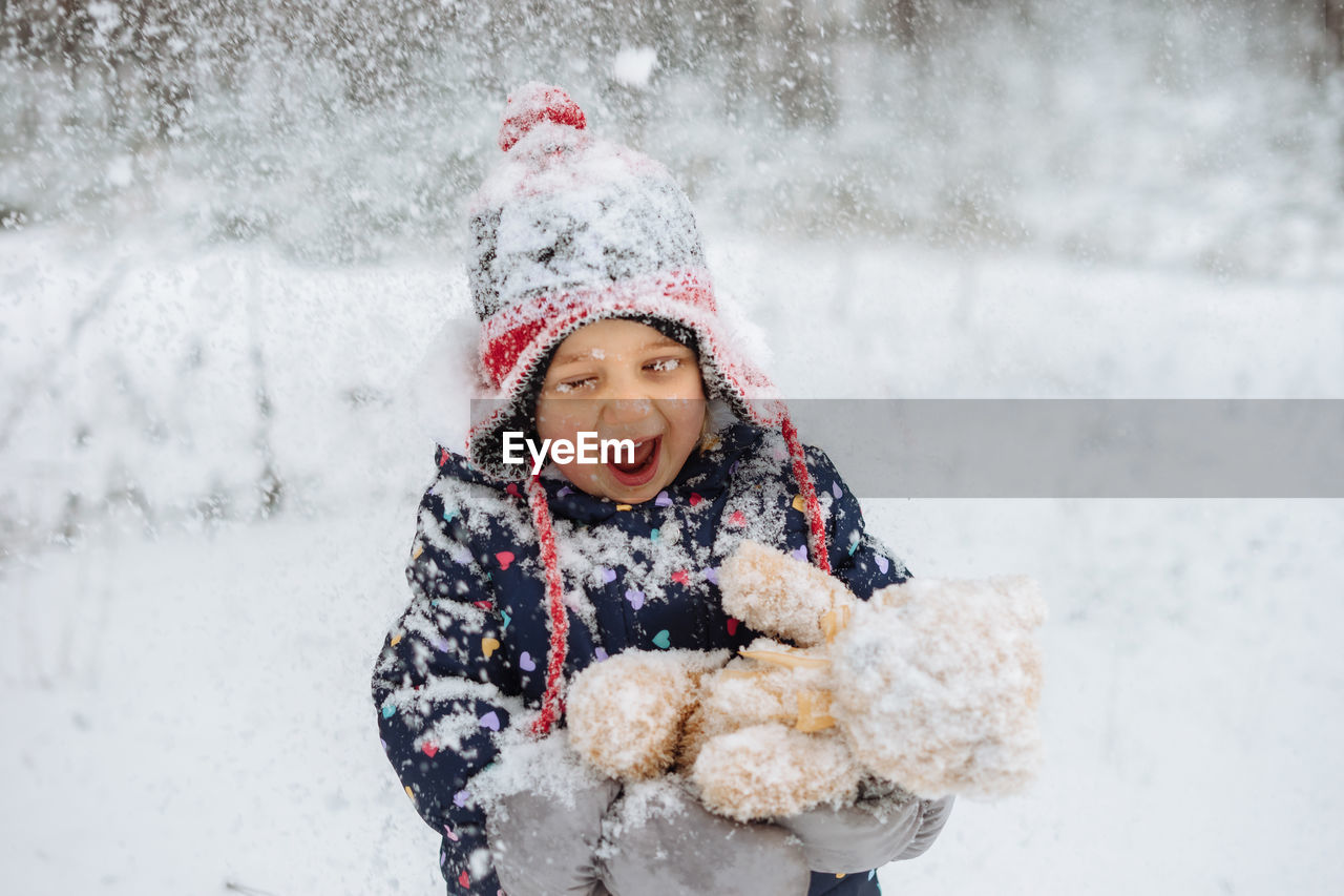 Happy child covered in snow playing outdoors.