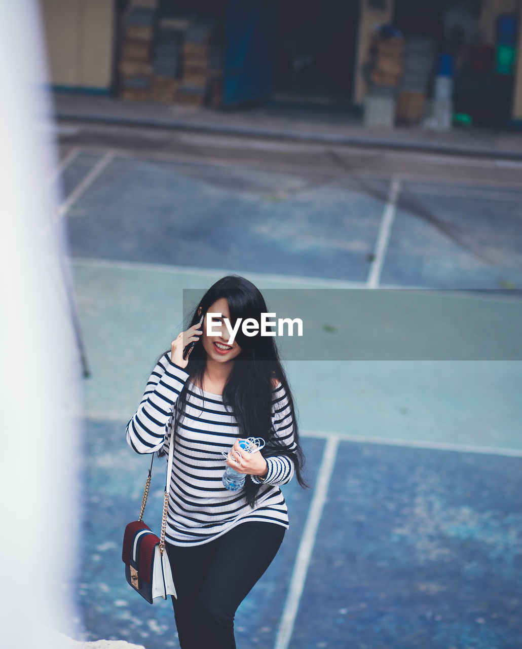 High angle view of young woman talking on phone while walking on steps