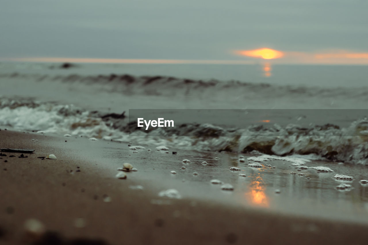 SCENIC VIEW OF BEACH AGAINST SKY AT SUNSET