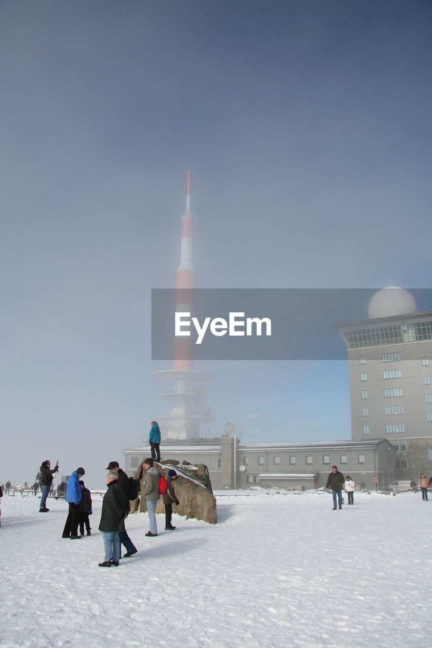 PEOPLE WALKING ON SNOW COVERED BUILDING