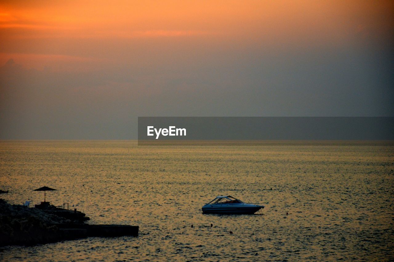 Boat in sea against sky during sunset