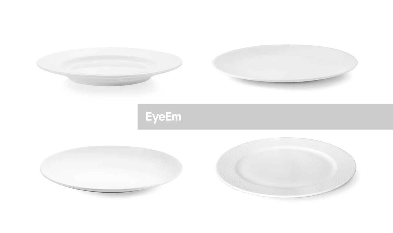 Close-up of empty plates against white background