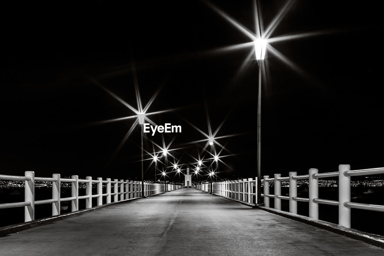 Illuminated pier against sky at night
