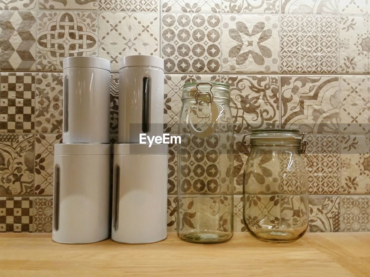 Glass jars and containers on table against wall