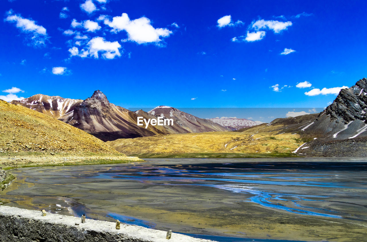 SCENIC VIEW OF LAKE BY SNOWCAPPED MOUNTAINS AGAINST BLUE SKY