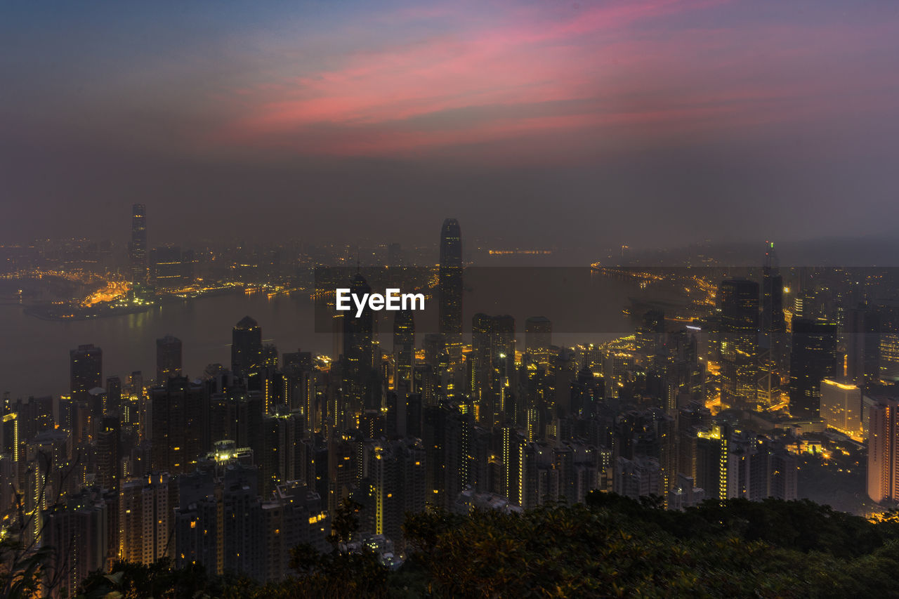 Illuminated buildings in city against sky during sunset