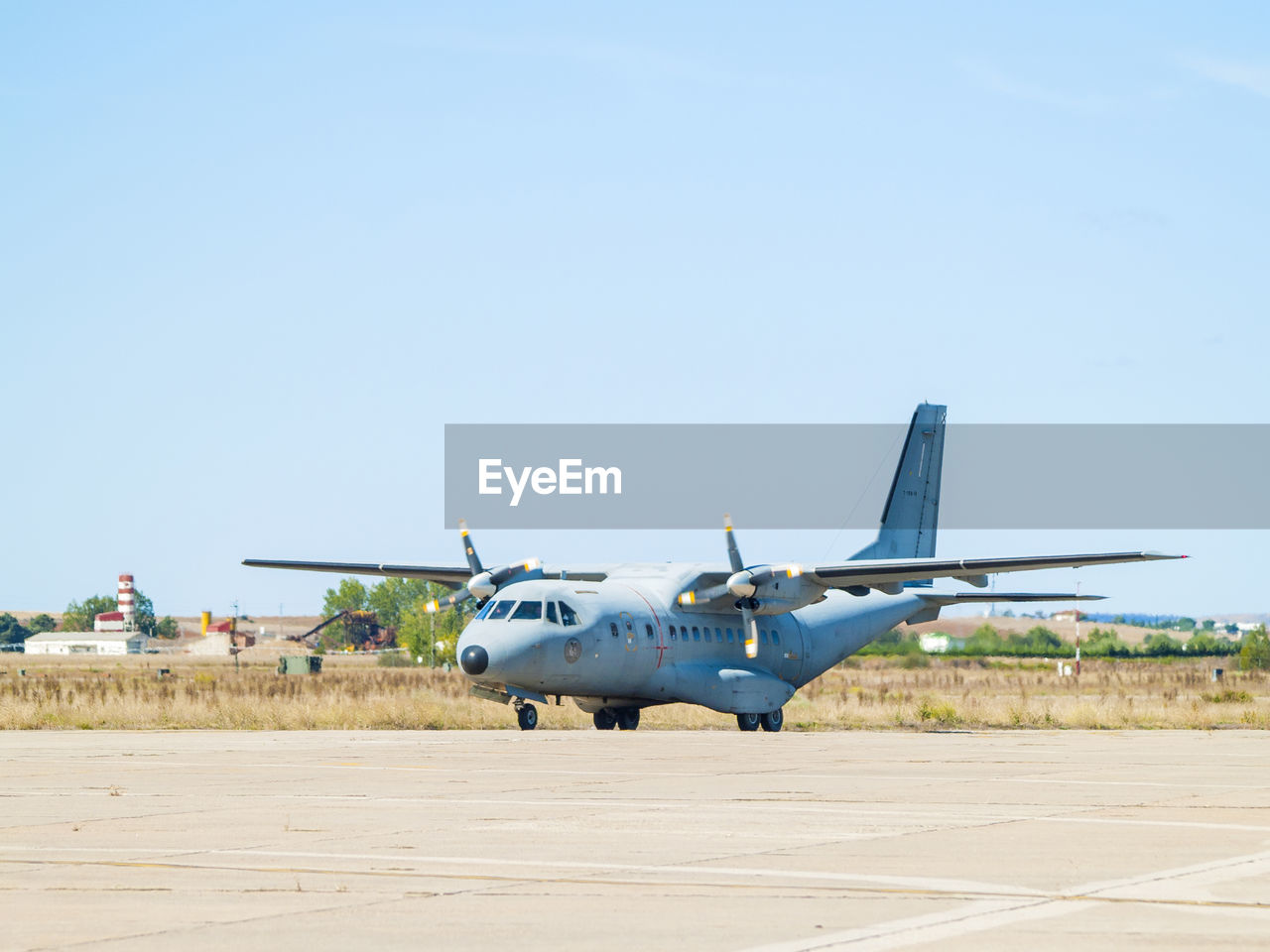 AIRPLANE FLYING OVER AIRPORT RUNWAY AGAINST CLEAR SKY