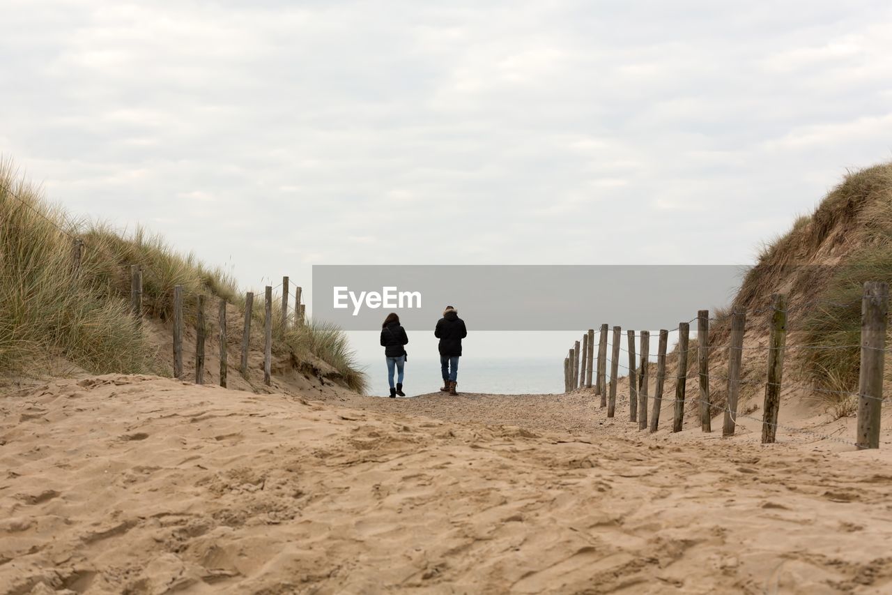 Rear view of man and woman walking on beach