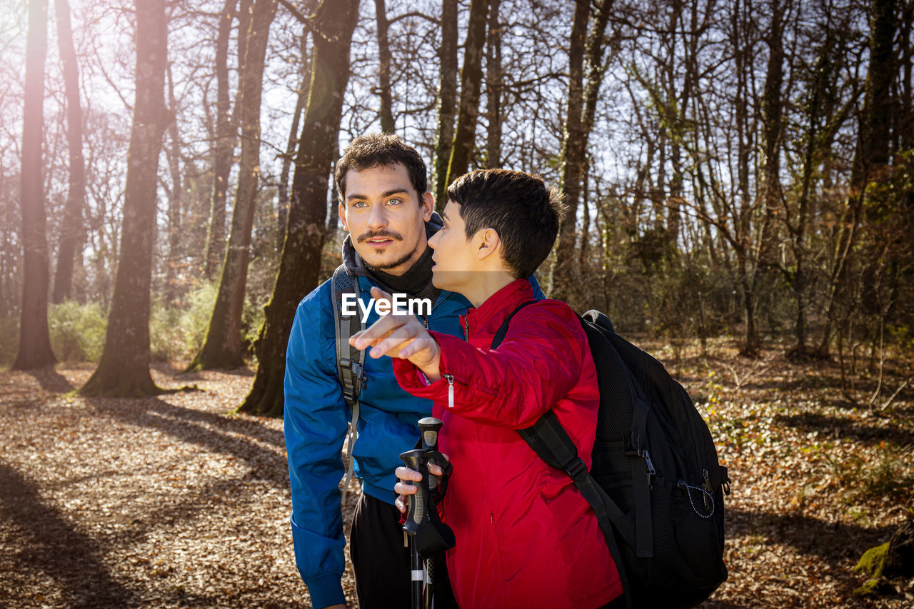 Beautiful young couple is hiking in the woods. the woman is pointing to her boyfriend.