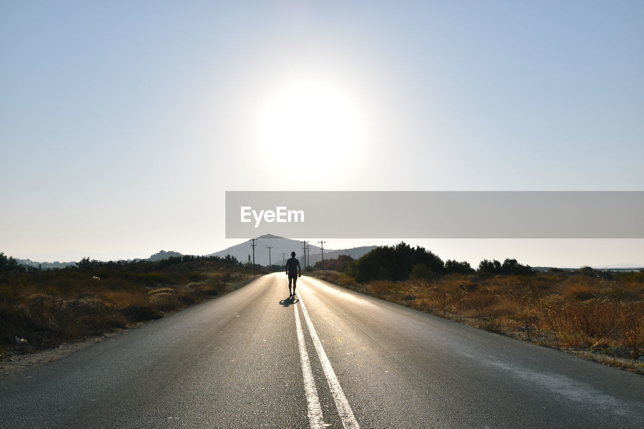 MAN ON ROAD AGAINST CLEAR SKY