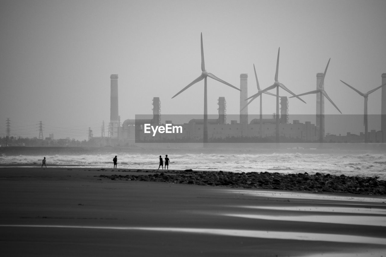 People on beach against sky in city