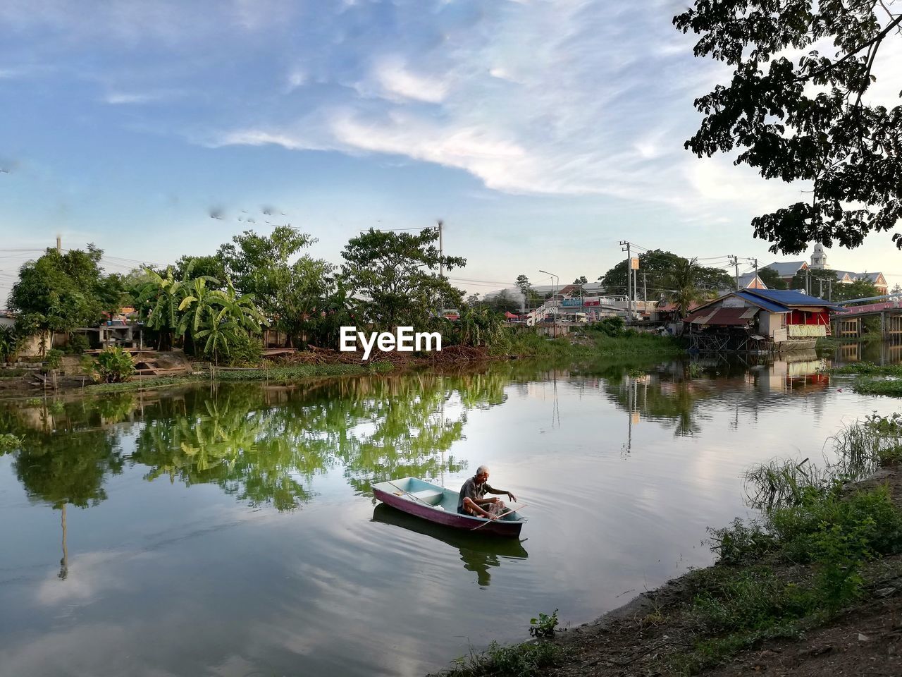 Man on boat in lake against sky