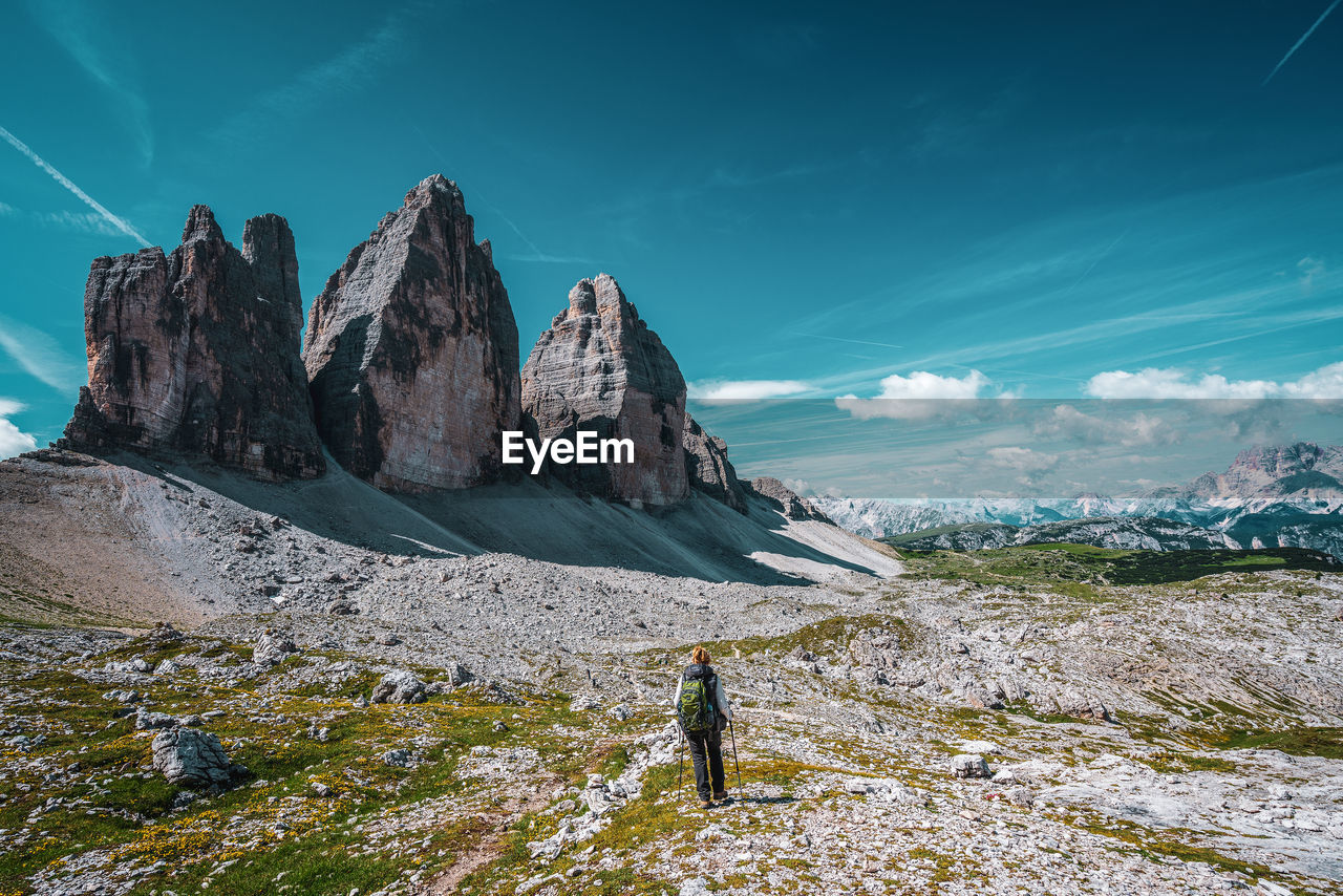 Backpacker on hiking trails in the dolomites, italy. view of the three peaks.