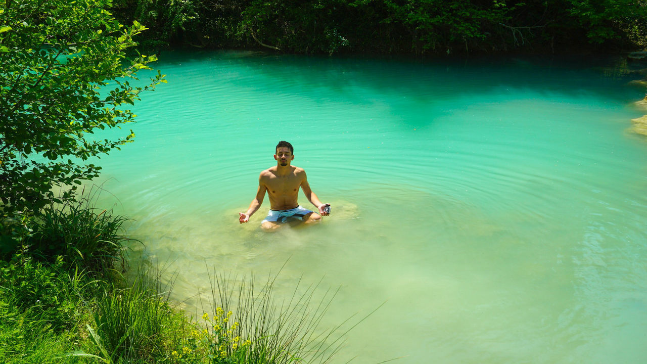 Shirtless man doing yoga in lake
