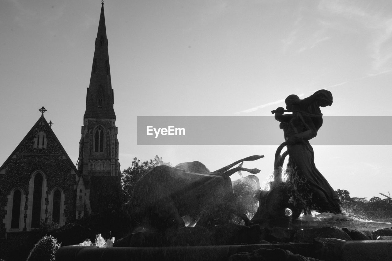 Statue against temple and building against sky