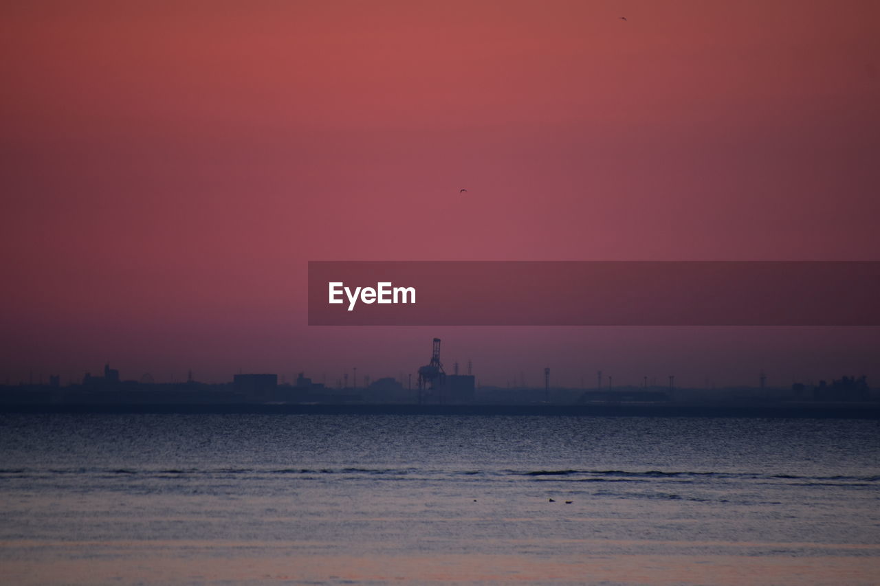 SILHOUETTE OF BUILDINGS AT SEASIDE