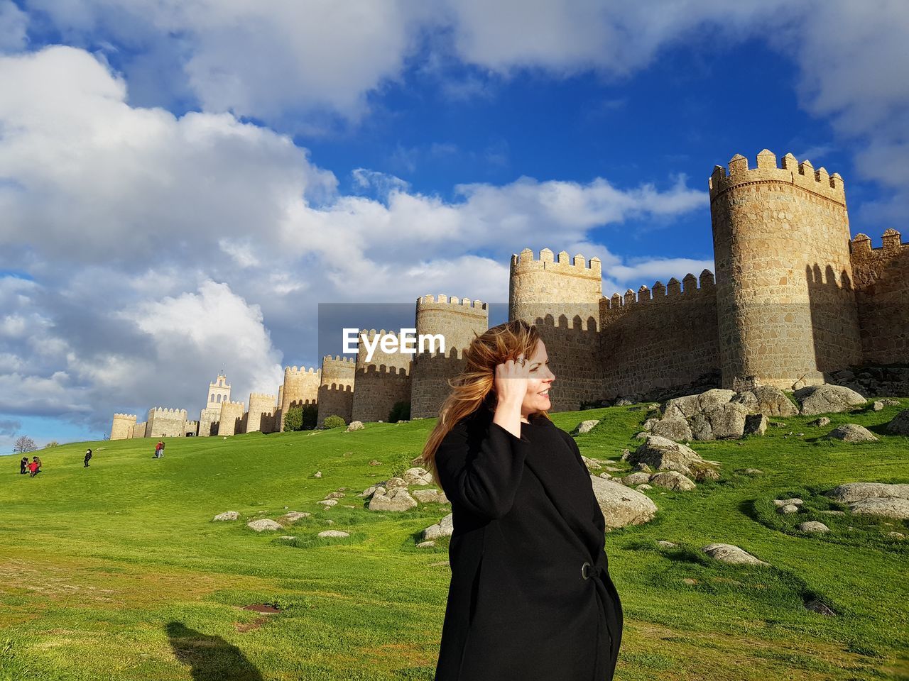 Woman standing on historical building against cloudy sky