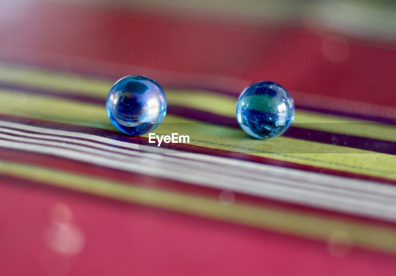 red, close-up, blue, no people, selective focus, sphere, reflection, macro photography, multi colored, purple, shiny, indoors, drop, marble